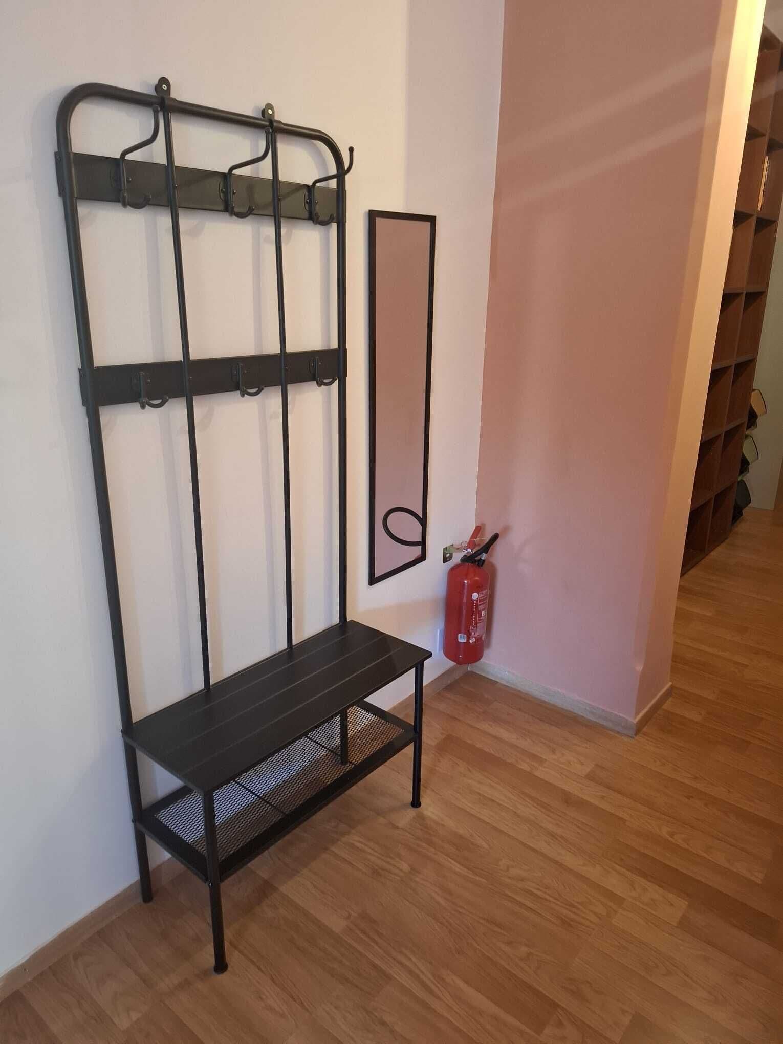 Et værelse med en sort metal bænk, et spejl på væggen og en rød brandslukker.
