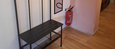 Et værelse med en sort metal bænk, et spejl på væggen og en rød brandslukker.