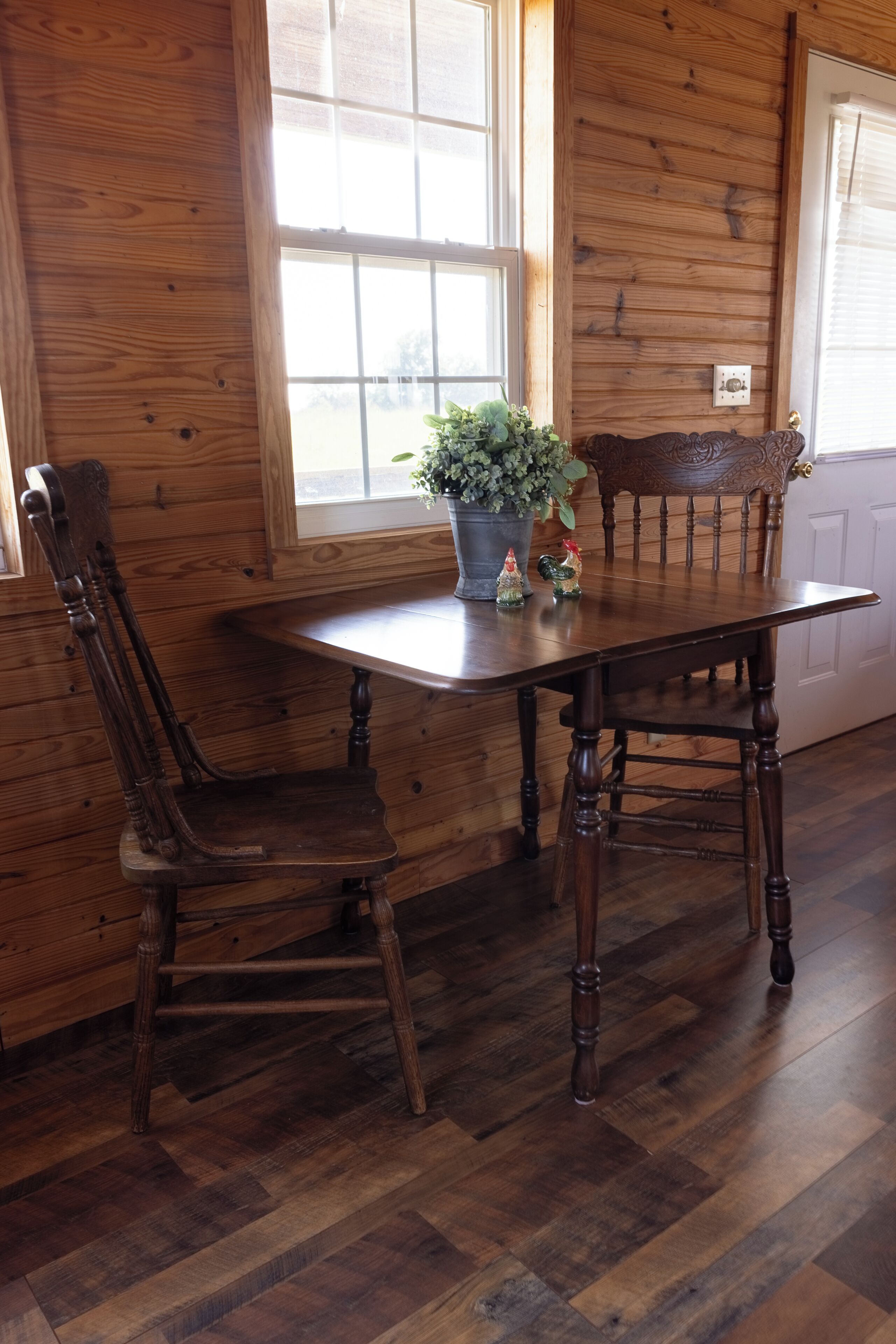 A wooden dining table with chairs, a potted plant, and two decorative figurines.