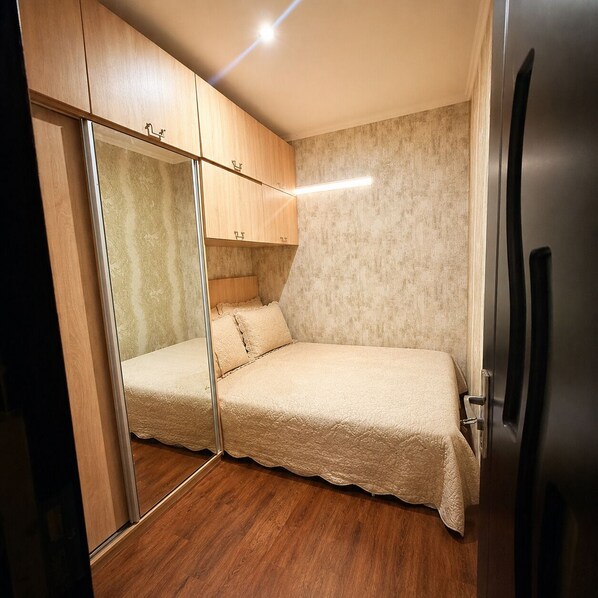 A bedroom with a bed, a wardrobe, and a mirror.
