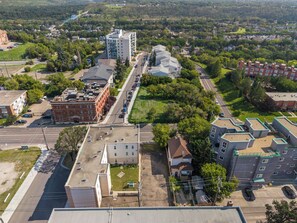 An aerial view of a residential area with a mix of single and multi-story buildings, roads, and greenery. - Downtown Edmonton Studio | AC, Parking (Edmonton)