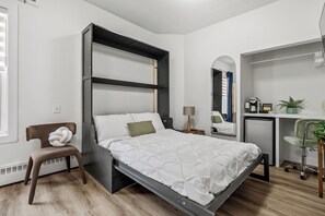 Un dormitorio moderno con una cama litera, un escritorio, una silla y una pequeña kitchenette.