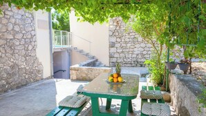A stone-walled outdoor area with a table and benches, a staircase, and a hanging basket with plants. - HAUS DALMATIEN-TUCEPI (MAKARSKA)