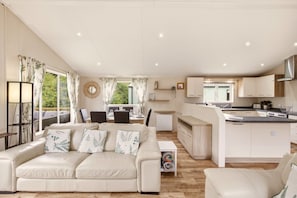 A spacious living area with a sofa, dining table, and kitchen area. - Cheviot Retreat Lodge - North East Escapes (Wooler)