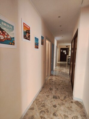 Ein Hotelgang mit gerahmten Kunstwerken an den Wänden und einem Marmorboden.