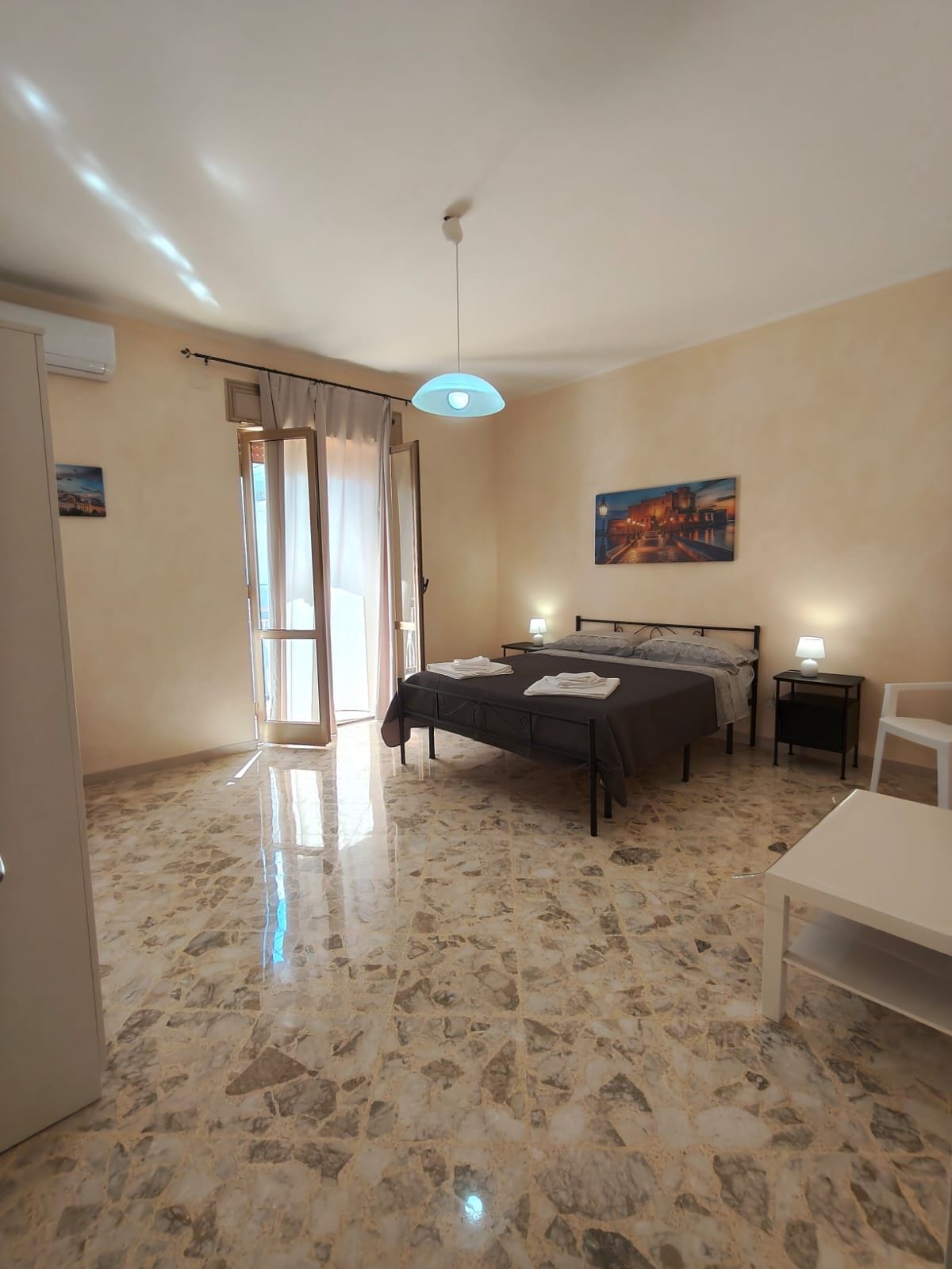 Una camera d'albergo con un letto, comodini, una scrivania e un quadro appeso al muro.