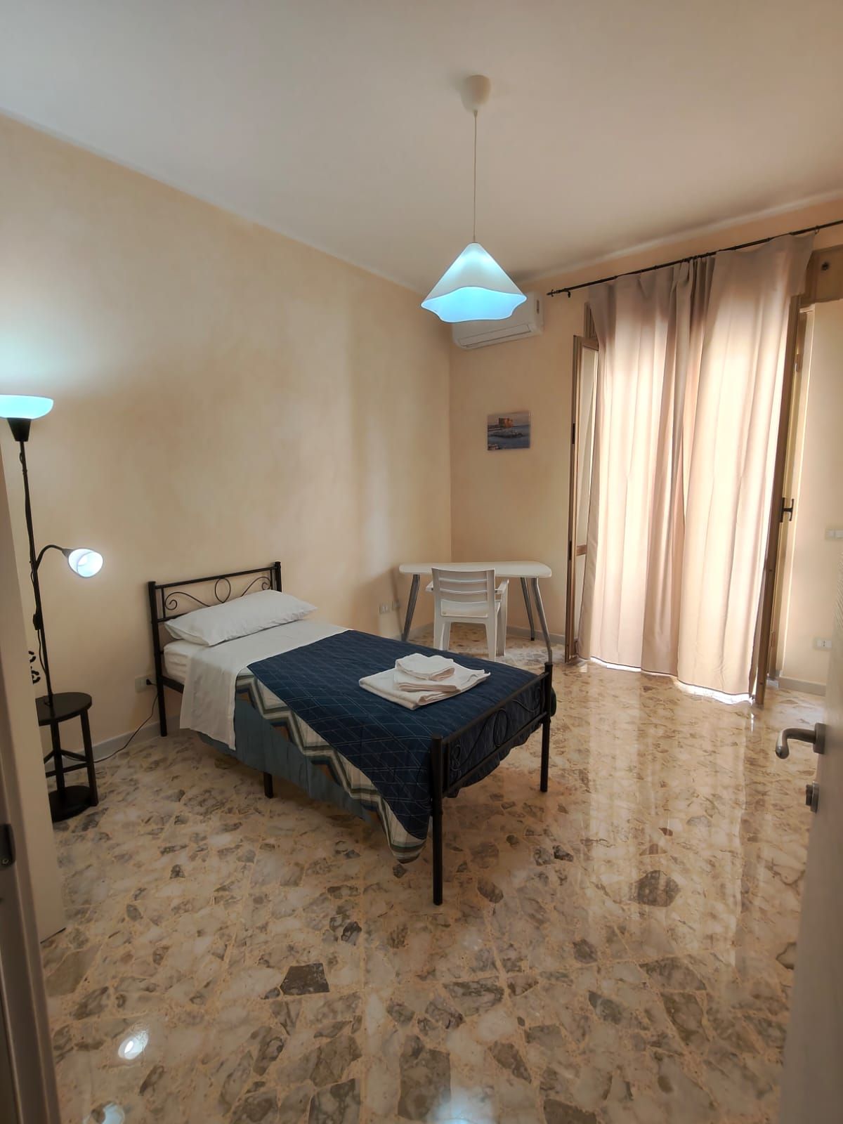 Ein Schlafzimmer mit Bett, Schreibtisch, Stuhl und Lampe.