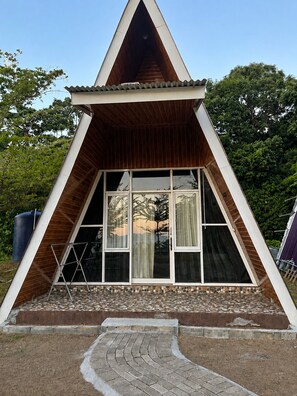 Um edifício triangular com telhado inclinado e janelas grandes.