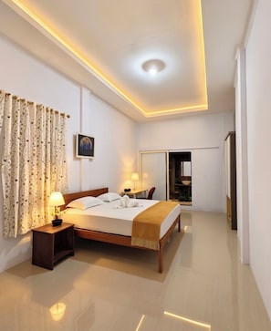 Quarto de hotel moderno com uma cama grande, mesas de cabeceira, um espelho e um guarda-roupa.