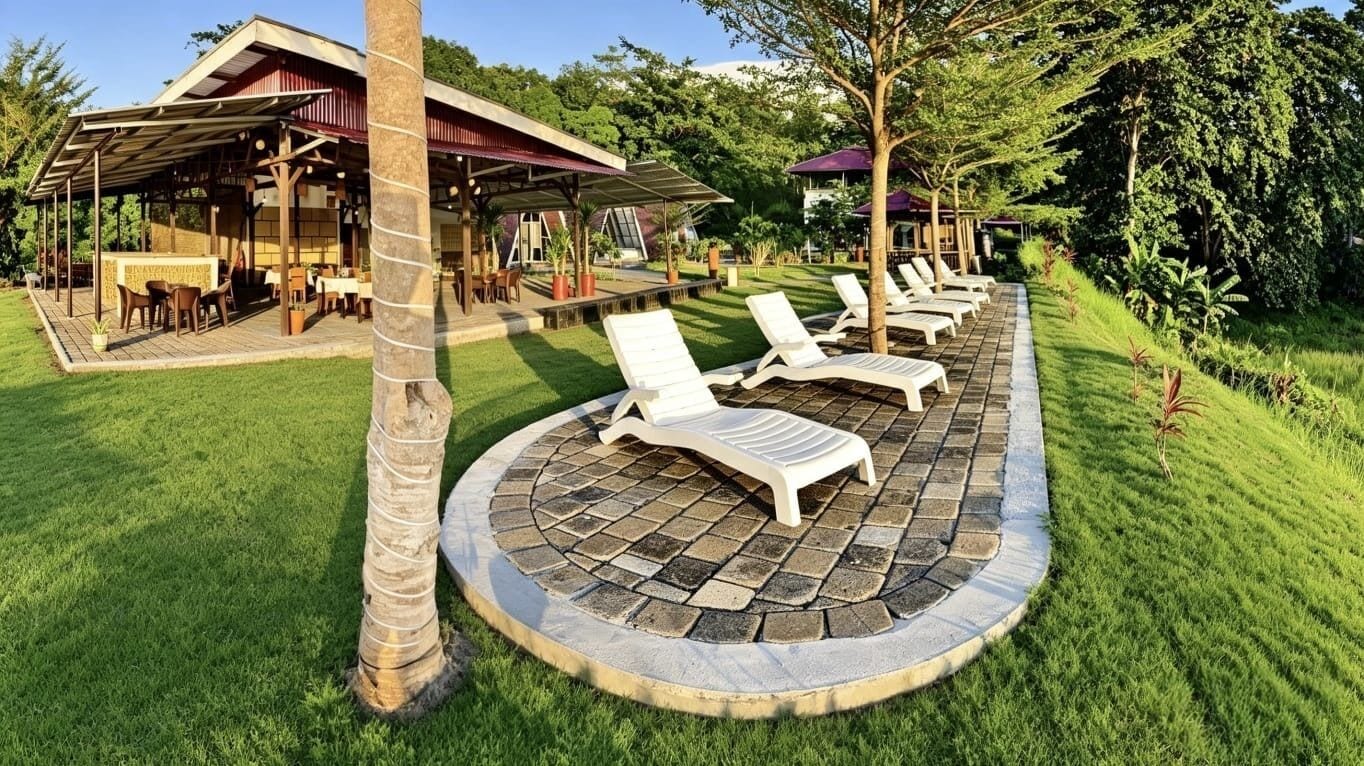 A resort with a covered outdoor seating area, lounge chairs, and a well-maintained lawn.