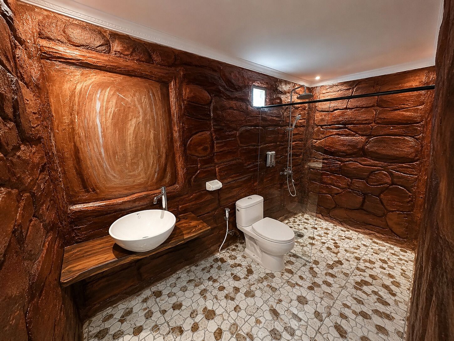 Une salle de bain avec un mur en pierre, un lavabo blanc, des toilettes et un espace douche.