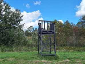 Eine Metallkonstruktion mit einer Plattform, umgeben von Gras und Bäumen.