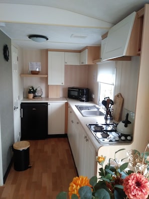 A compact kitchen with a microwave, stove, sink, and a small refrigerator.