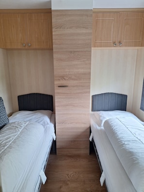 A room with two beds, wooden wardrobe cabinets, and a central panel.