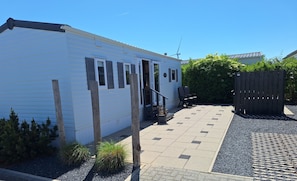 A white mobile home with a patio area, a wooden fence, and a small garden.