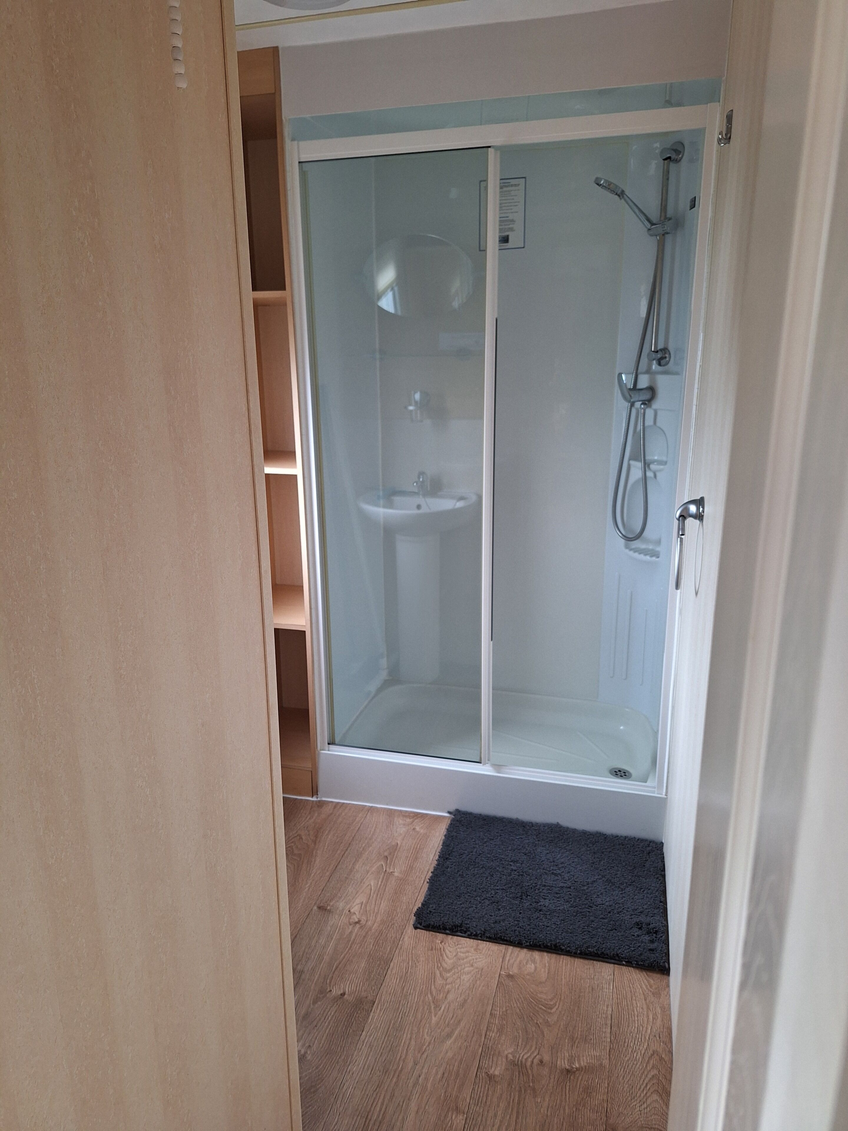 Eine Duschkabine mit Glastür, ein Waschbecken und ein Duschkopf.