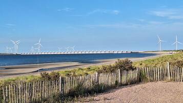 Eine Küstenlandschaft mit Windkraftanlagen, einem Sandstrand und einem Holzzaun.