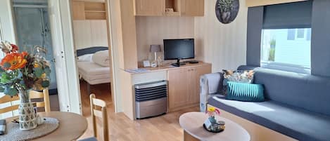 A compact living space with a bed, a sofa, a dining area, and a kitchenette.