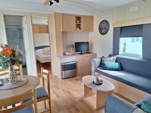 A compact living space with a bed, a sofa, a dining area, and a kitchenette.