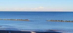 A beach with calm waters and a rocky outcrop in the distance. - Vrbo Property (Lido di Pomposa)