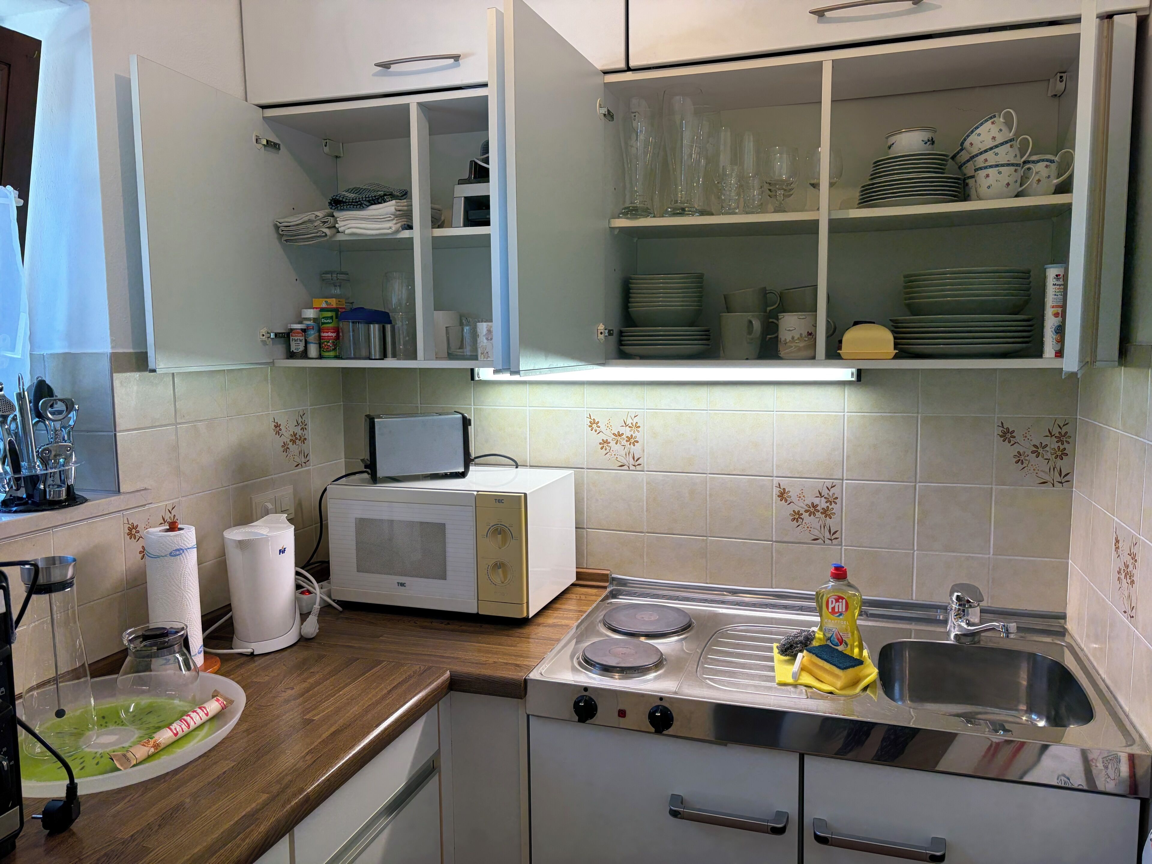 Eine Küche mit Mikrowelle, Toaster, Herd und verschiedenen Küchenutensilien.