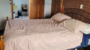Quarto com cama, cabeceira de madeira, mesa de cabeceira e parede com frases motivacionais.