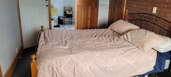 A bedroom with a bed, a wooden headboard, a bedside table, and a wall with motivational quotes.