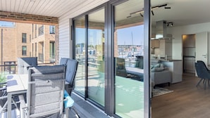 A modern apartment with a balcony, a dining area, and a kitchen. - Listing No. 303 “Baltique” in Travemünde, featuring a large south-facing loggia and harbor views (Travemünde)