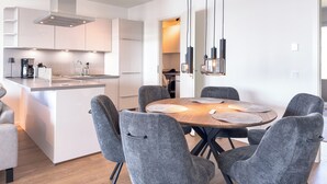 A modern kitchen with a central island, grey upholstered chairs, and pendant lighting. - Listing No. 303 “Baltique” in Travemünde, featuring a large south-facing loggia and harbor views (Travemünde)