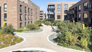 A modern building with multiple floors, a central courtyard with pathways, and surrounding greenery. - Listing No. 303 “Baltique” in Travemünde, featuring a large south-facing loggia and harbor views (Travemünde)