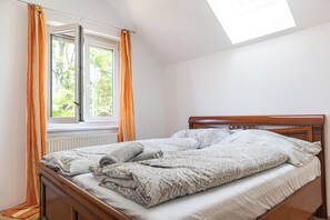 A bedroom with a wooden bed, a window with curtains, and a skylight.