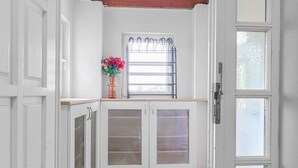 A kitchen with white cabinets, a window with a metal grill, and a vase with flowers. - Private Villa Room for 4 | Garden Access (Vienna)