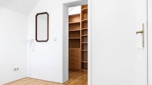Habitació amb terra de fusta, una porta blanca i un armari amb diversos calaixos.