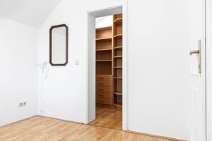 A room with a wooden floor, a white door, and a closet with multiple drawers.