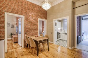 A spacious living area with a wooden dining table, comfortable seating, a brick wall, and a kitchen visible through an open doorway. - Premium House, 3br, Renovated, Best Loc Kadıköy (Istanbul)