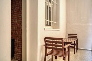 A narrow corridor with a brick wall on one side, a white wall with a window on the other, and a wooden bench and table set against the wall. - Premium House, 3br, Renovated, Best Loc Kadıköy (Istanbul)