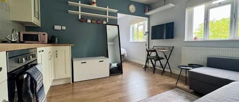 A compact living space with a kitchenette, a dining area, and a seating area with a sofa and a TV.