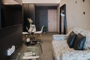 A modern living room with a glass coffee table, a sofa with patterned cushions, and a dining area with a glass table and chairs. - Loft one block from the Monumento a la Revolución, between Centro Histórico and Reforma. Private balcony, rooftop with incredible views, gym, garden, and a coworking area among the shared amenities. (Tabacalera)