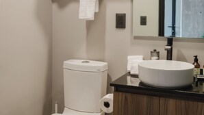 Ein modernes Badezimmer mit Toilette, Waschbecken und Spiegel.