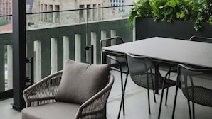 Ein moderner Außenbereich mit Korbstühlen und einem Tisch, mit Blick auf eine Stadtlandschaft, die von einem markanten, kuppelförmigen Gebäude geprägt ist.