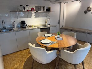 Eine moderne Küche mit Essbereich, ausgestattet mit einem Holztisch, vier Stühlen, einer Mikrowelle und einer Kaffeemaschine.
