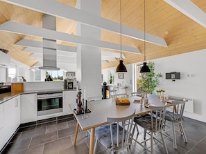 A modern kitchen with white cabinetry, a central island, and a dining area with a round table and chairs. - "Helma" - 580m to the fjord by Interhome (Ulfborg)