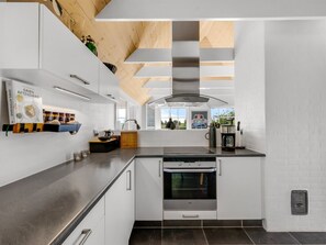 A modern kitchen with built-in appliances, a large window, and a wooden ceiling. - "Helma" - 580m to the fjord by Interhome (Ulfborg)