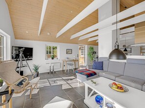 A modern living room with a sofa, a coffee table with fruit, a tripod, and a television. - "Helma" - 580m to the fjord by Interhome (Ulfborg)