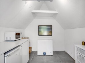 Une petite cuisine équipée d’un four à micro-ondes, d’un réfrigérateur et ornée d’un tableau au mur.