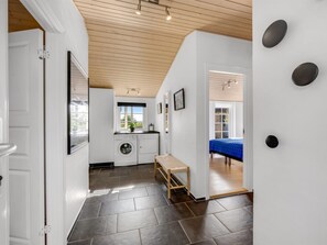 A laundry room with a washing machine and dryer, a bench, and a view of a bedroom with a bed. - "Helma" - 580m to the fjord by Interhome (Ulfborg)