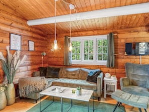 L'intérieur d'une cabane en rondins, avec un canapé, un fauteuil et une petite table.