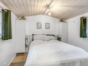 Ein Schlafzimmer mit einem Bett, einem Kleiderschrank und zwei gerahmten Bildern an der Wand.