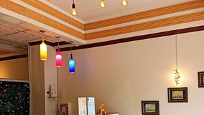 A reception desk with a marble top, a red accent wall, and a wooden ceiling.