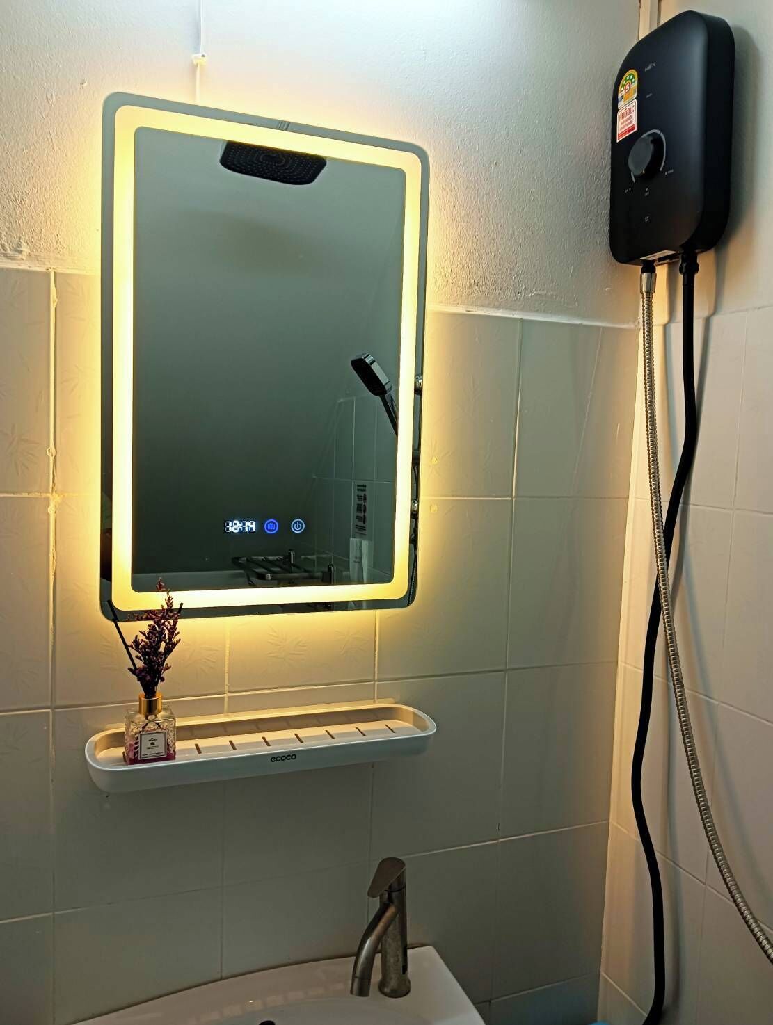 A bathroom with a wall-mounted mirror, a handheld showerhead, and a sink with a faucet.